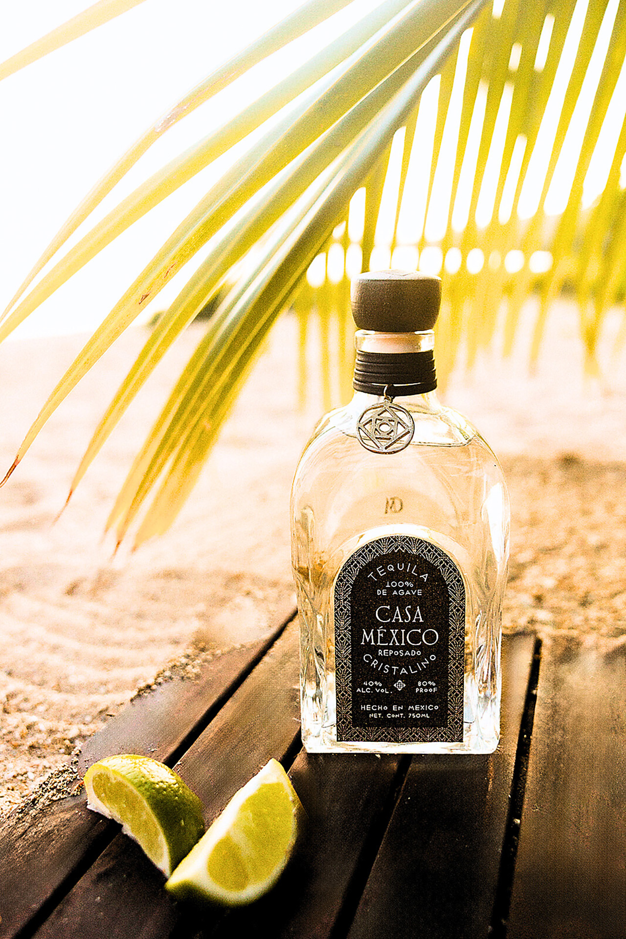 Bottle of Casa Mexico Cristalino Tequila with limes by the Beach